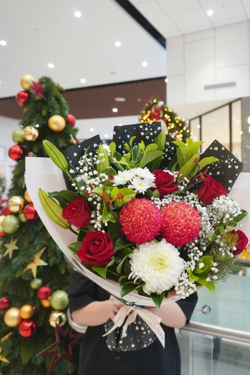 Bouquet of flowers held by a person with a Christmas tree in the background